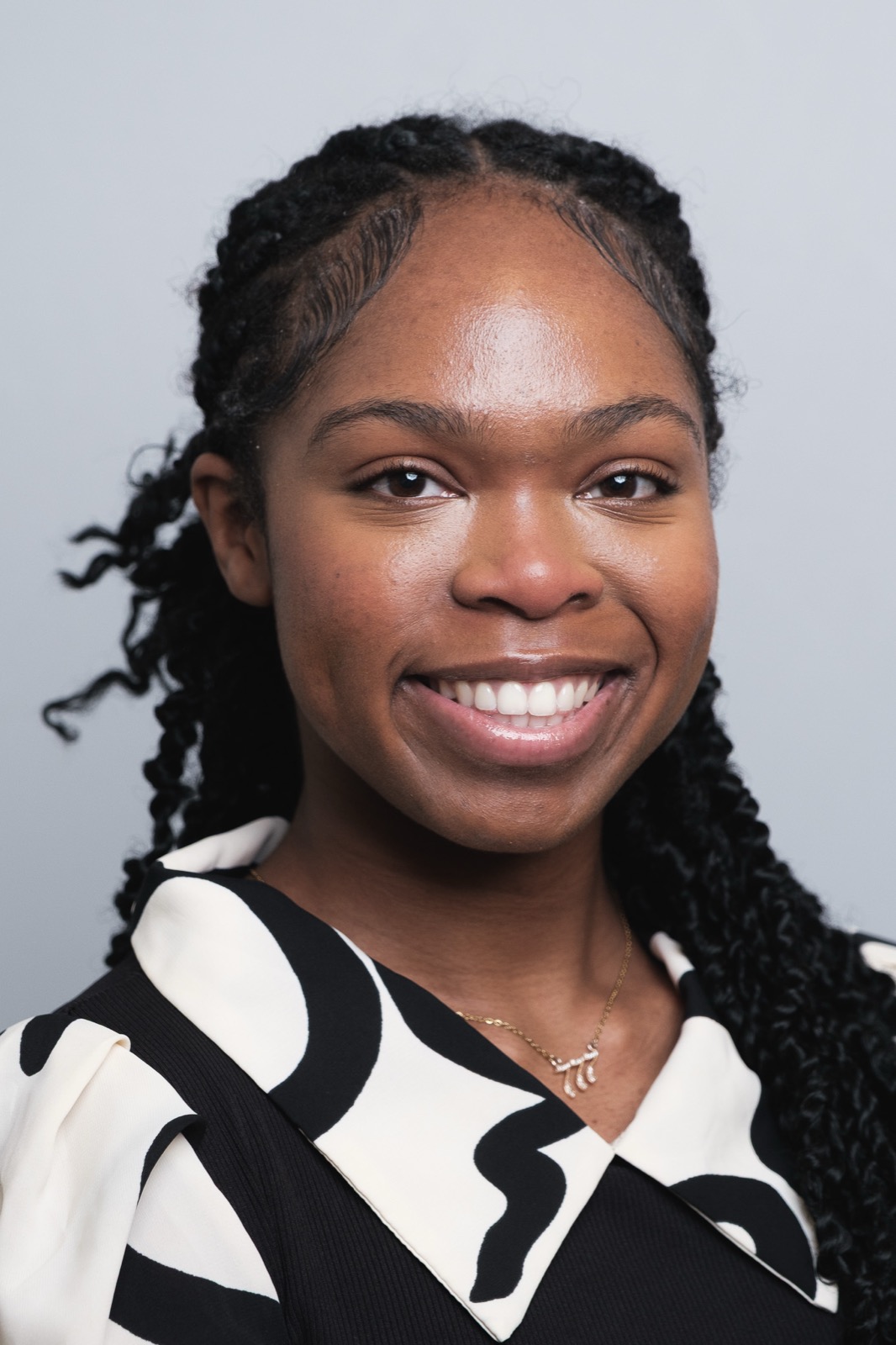 Studio headshot, woman with braids smiling