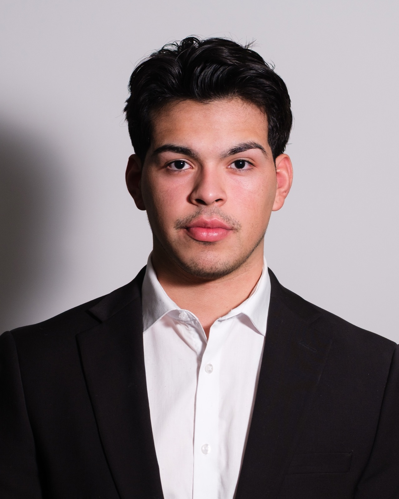 Studio headshot, man in black suit