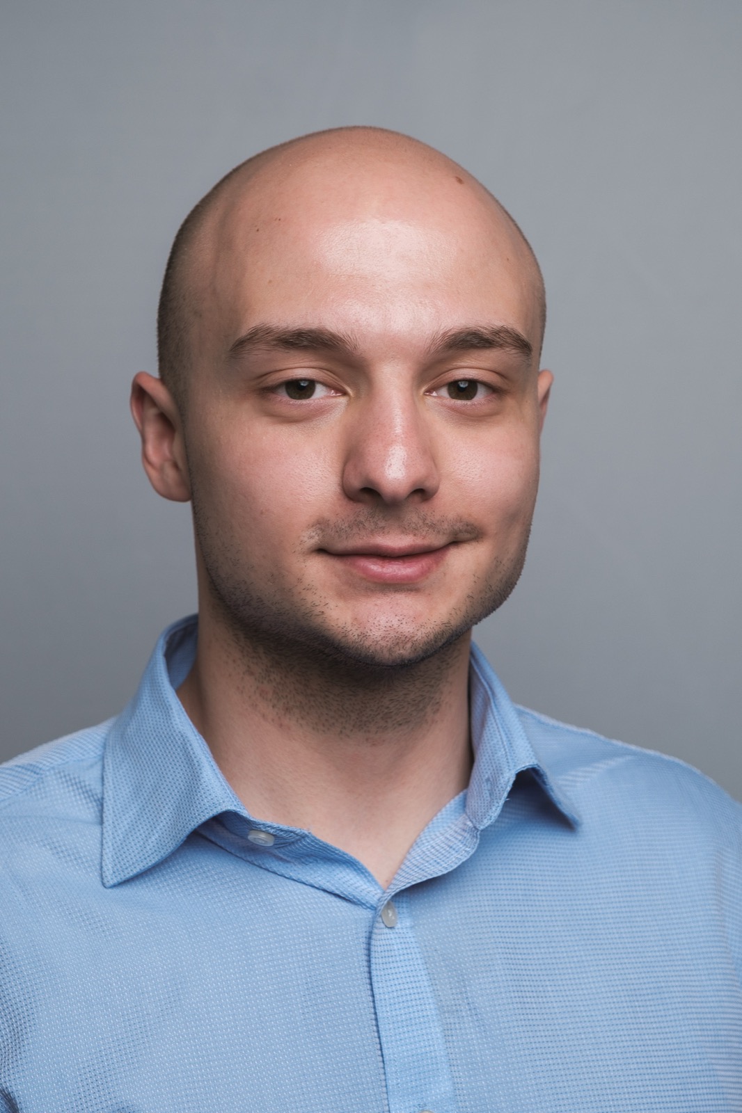 Studio headshot, man in blue shirt