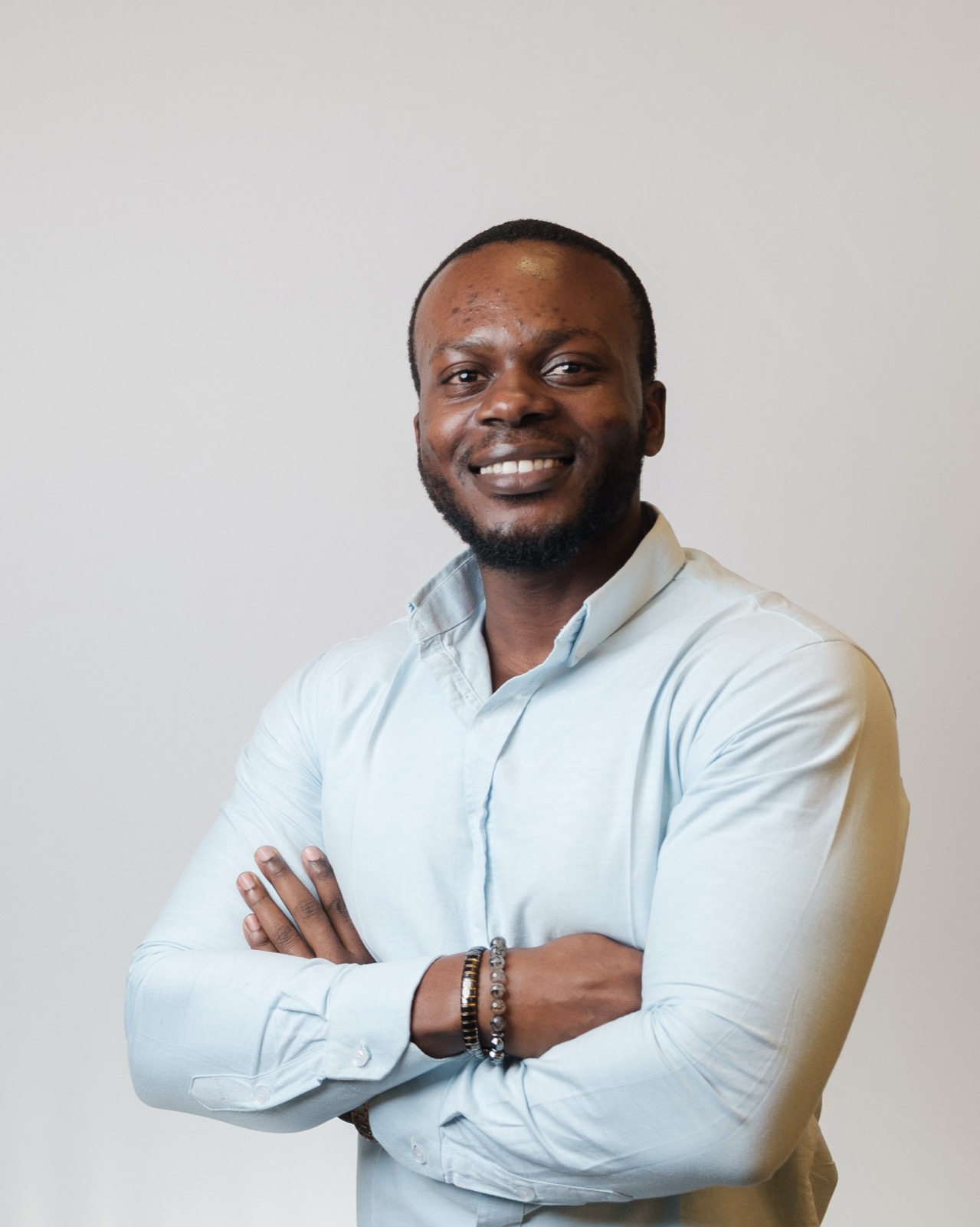 Studio headshot, man in light blue shirt smiling