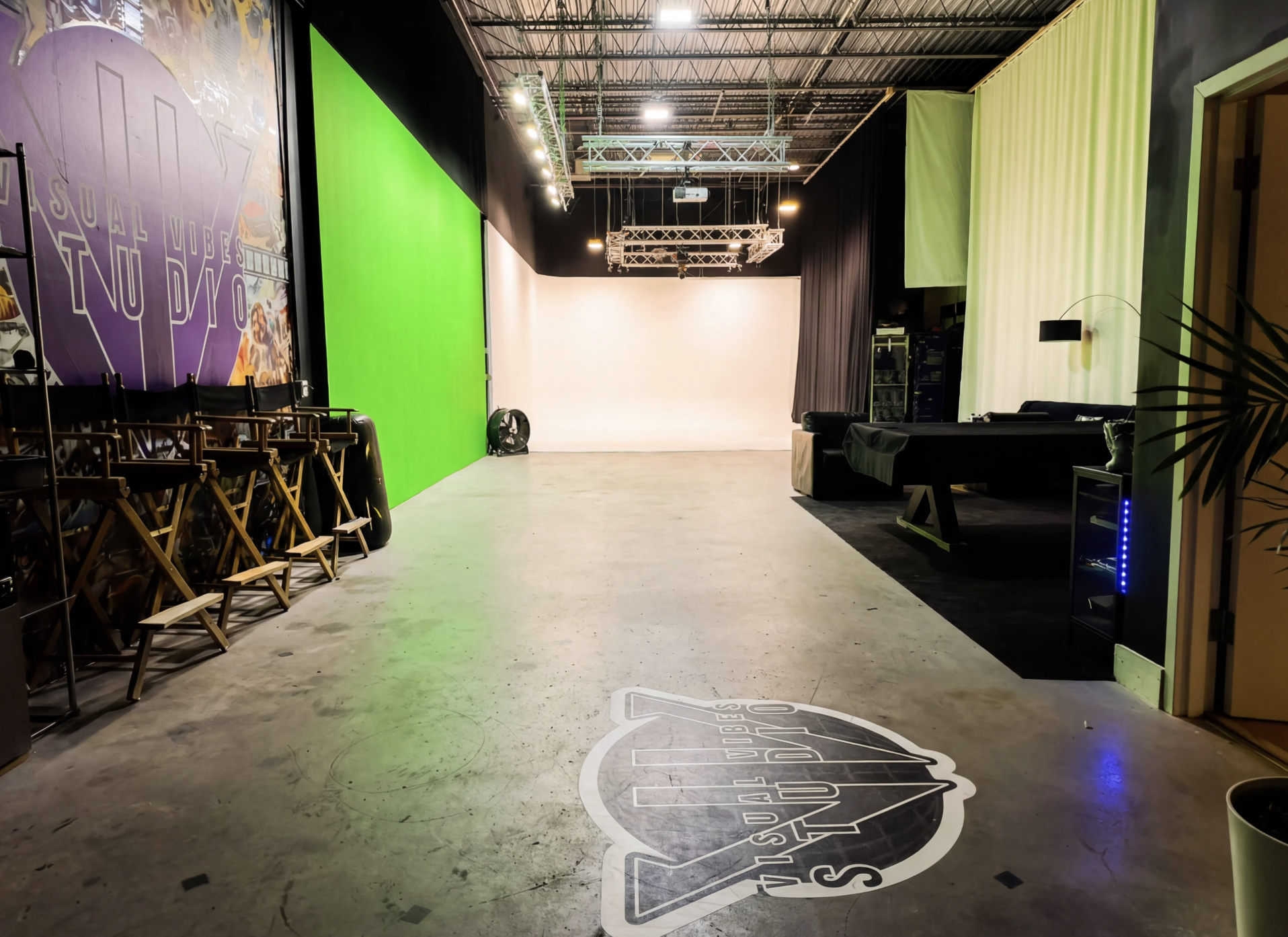 Inside Visual Vibes Studio — 3,500 sq ft production floor with green screen, white cyc, lighting truss, and Visual Vibes branding.