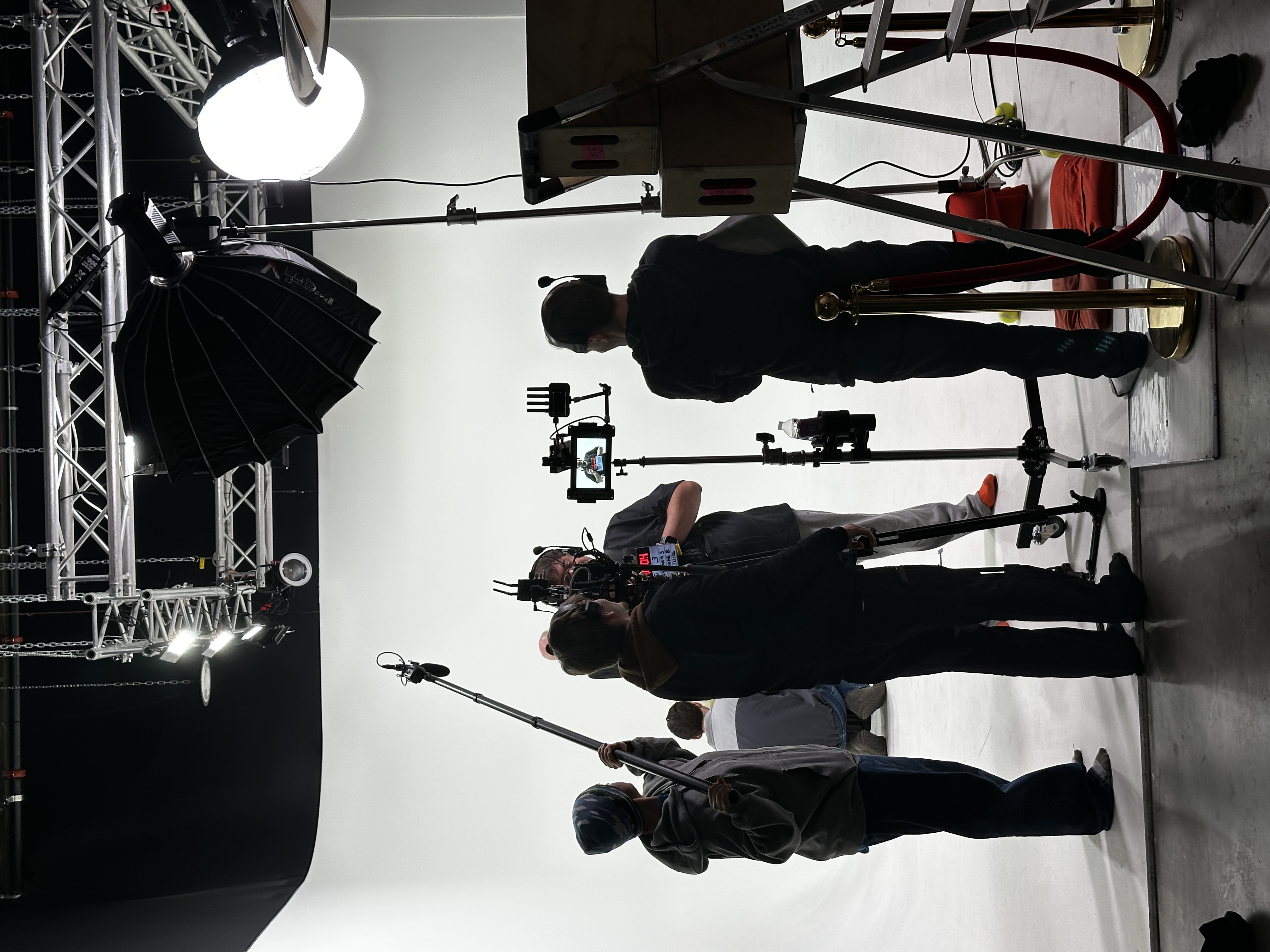 Full production crew on white cyclorama with camera rig and boom