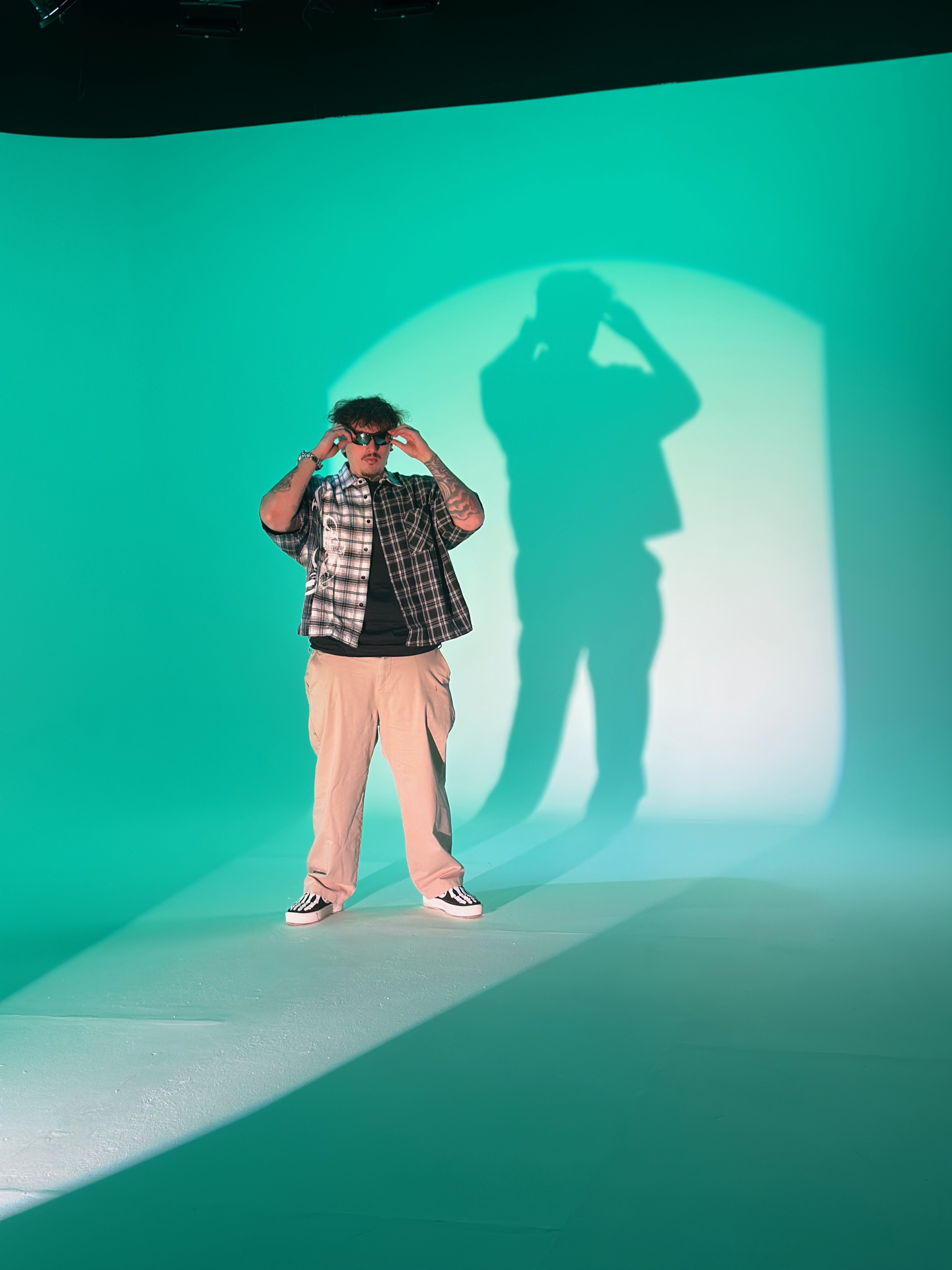 Artist in flannel with projected spotlight on green cyc wall